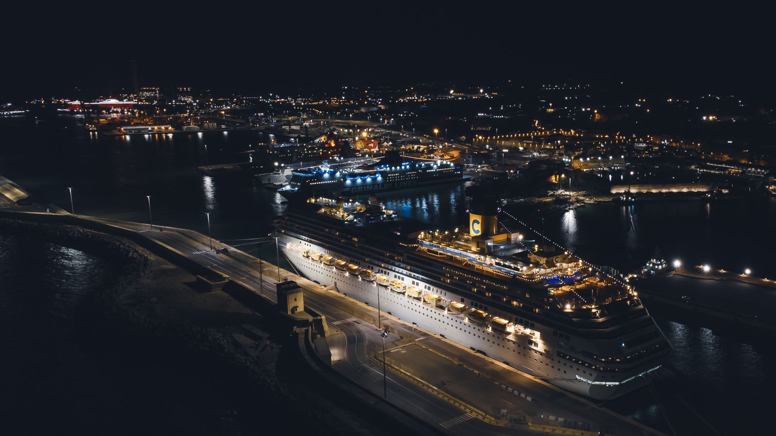 Aerial night view of a brightly lit cruise ship moored in a harbor