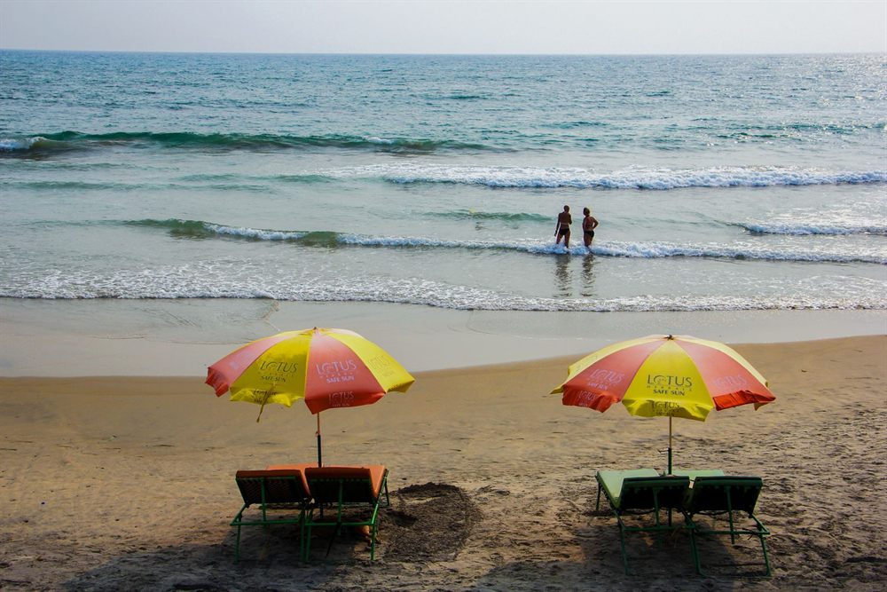 Two beach umbrellas and loungers facing the waves on a sunny tropical beach