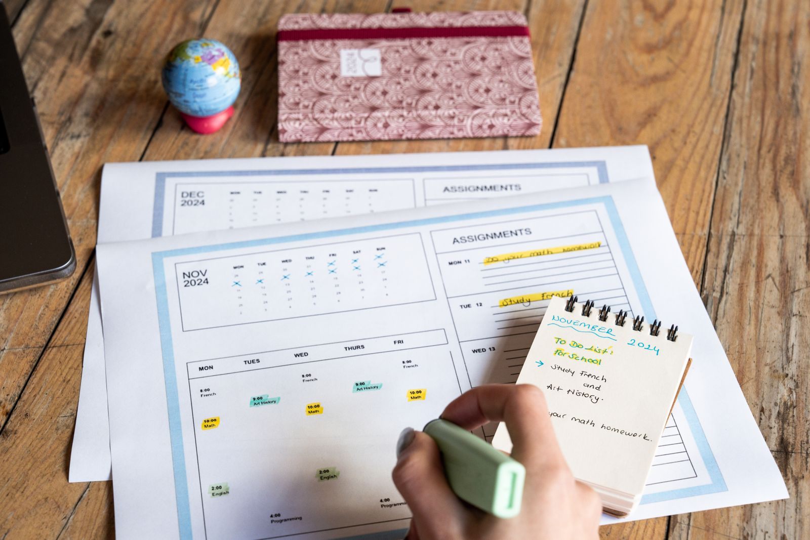 Person planning with a monthly calendar and notepad on a wooden table