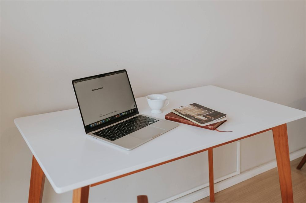 Laptop, coffee cup and books on a white desk ready for comparing quotes